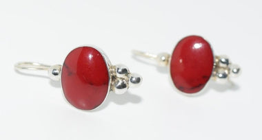 A pair of vintage Mexico 925 sterling silver oval hook earrings with a bright red Howlite centerpiece.